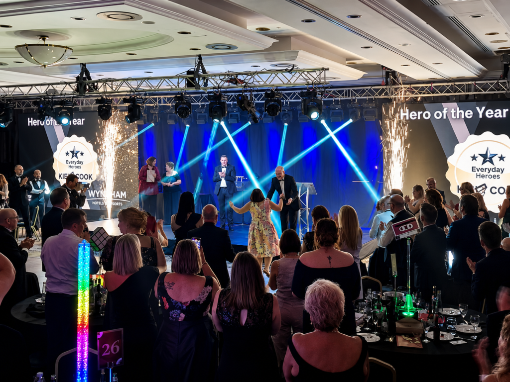 Corporate awards show production with stage lighting, pyrotechnics, LED screens, and audience during a live gala event.