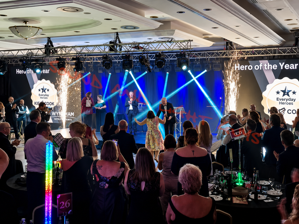 Corporate awards show production with stage lighting, pyrotechnics, LED screens, and audience during a live gala event.